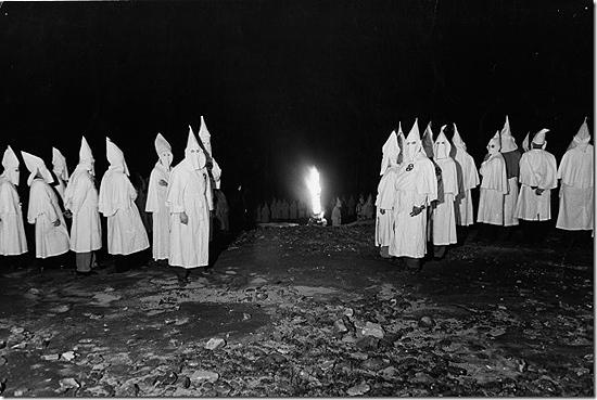 Ku Klux Klan members standing near a burning cross during an initiation ceremony, Atlanta, Georgai, 1948<br/>