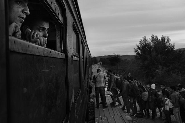 Rwand Ali, from Syria, watches refugees board a train to the Serbian border, 2015<br/>