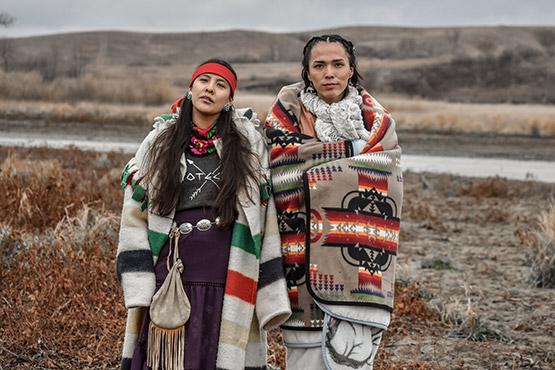 Photo: Two Dine woman hold strong in sovereignty, only speaking their ancestral language at Turtle Island, Thanksgiving, 2016 Archival Pigment Print #2254