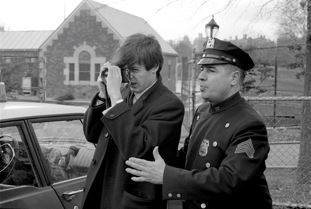 Paul McCartney with camera and Policeman, 1964