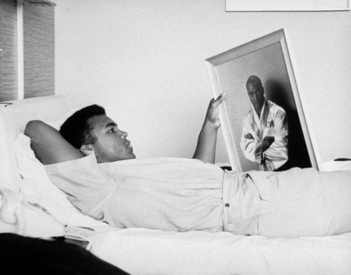  Cassius Clay (now Muhammad Ali) resting, holding picture of Sonny Liston, 1964