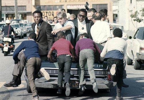 The Kennedy campaign travels through the Watts section of Los Angeles on the last day before the primary, 1968<br/>