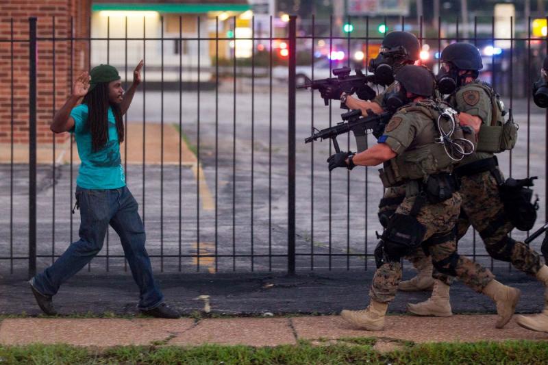 Rashaad Davis, 23, backs away as St. Louis County police officers approach him with guns drawn and eventually arrest him, Ferguson, Missouri, August 11, 2014<br/>