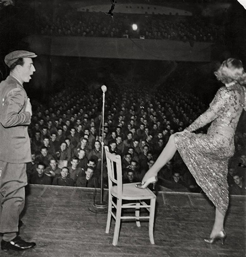 Marlene Dietrich posing seductively as she exhibits her famous leg while entertaining troops in Germany, February, 1945