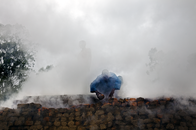Photo: Men work on a brick kiln in Anosibe. This is a very inefficient use of wood, which is the main source of fuel for burning the clay to make the bricks. Madagascar, 2010 Archival Pigment Print #2594