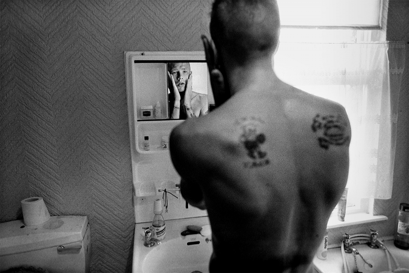 Photo: A teenager from Belfast’s working-class Protestant neighborhood of Tiger’s Bay, checks himself in the mirror in Belfast. Northern Ireland, 1989 Archival Pigment Print #2599