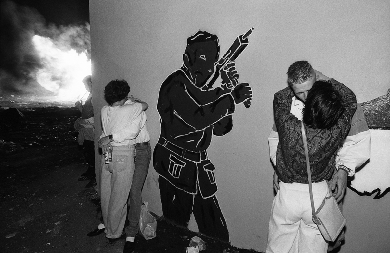 Photo: Brian Crothers and his girlfriend Sharon, teenagers from Belfast’s working-class Protestant neighborhood of Tiger’s Bay, celebrate the 11th Night Bonfire under the ever-present symbol of the paramilitary in Belfast, Northern Ireland, 1989 Archival Pigment Print #2601