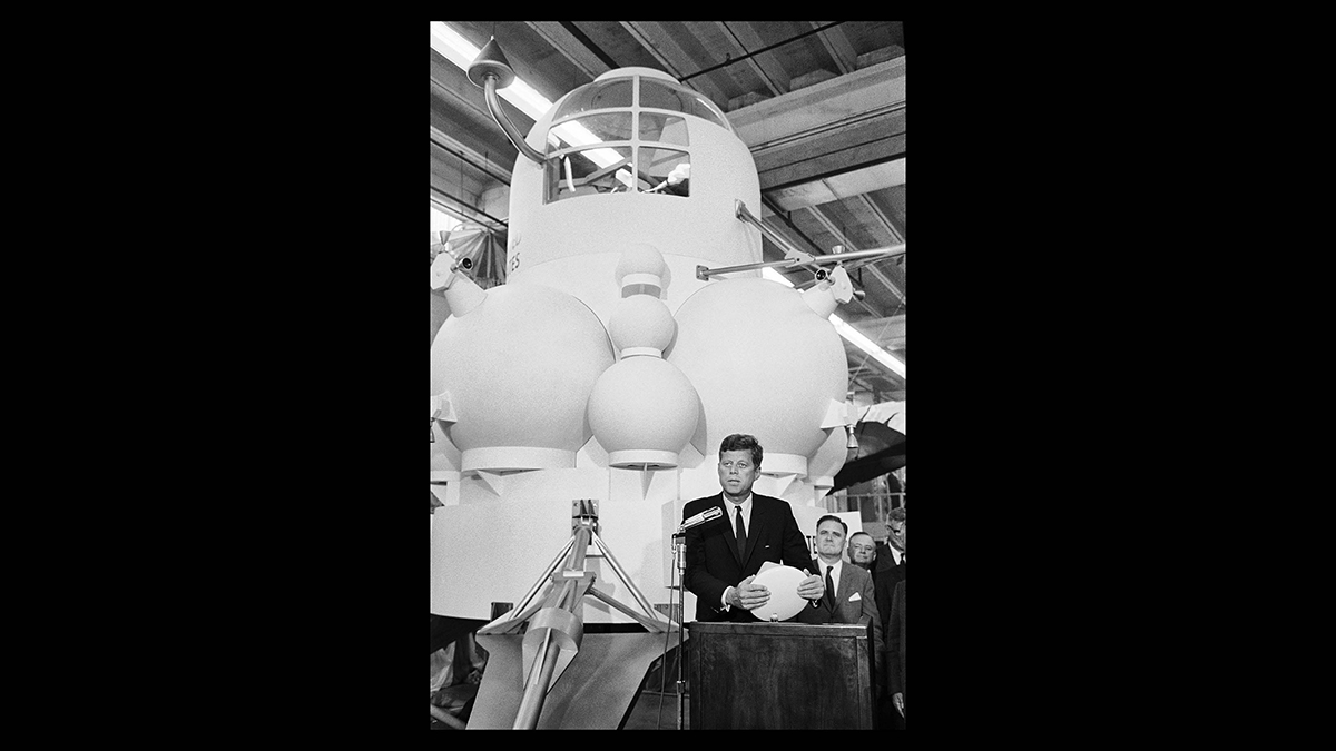 President John F. Kennedy stands in front of the Lunar Module mock up after being presented with an Apollo Command Module Model after touring the Manned Spacecraft Center Rich Building in Houston, Texas.