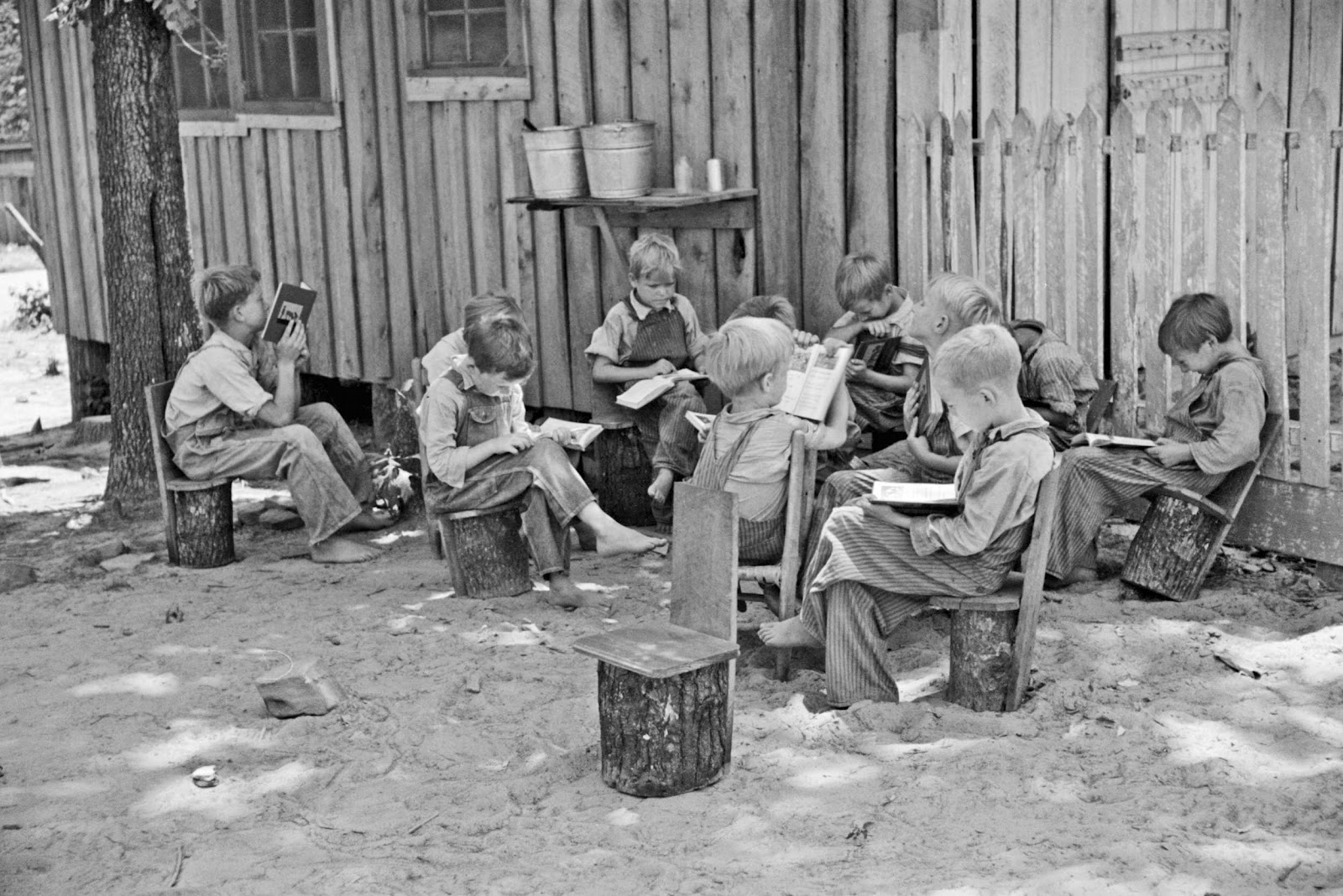 Schoolboys reading books in an outdoor classroom for migrant children at Skyline Farms, near Scottsboro, Alabama June 1936