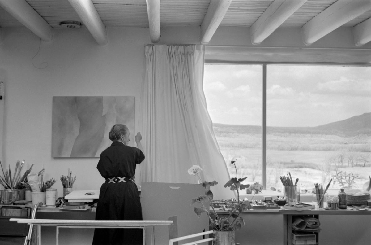 Georgia O'Keeffe opens her studio curtains, Abiquiu, New Mexico, 1960