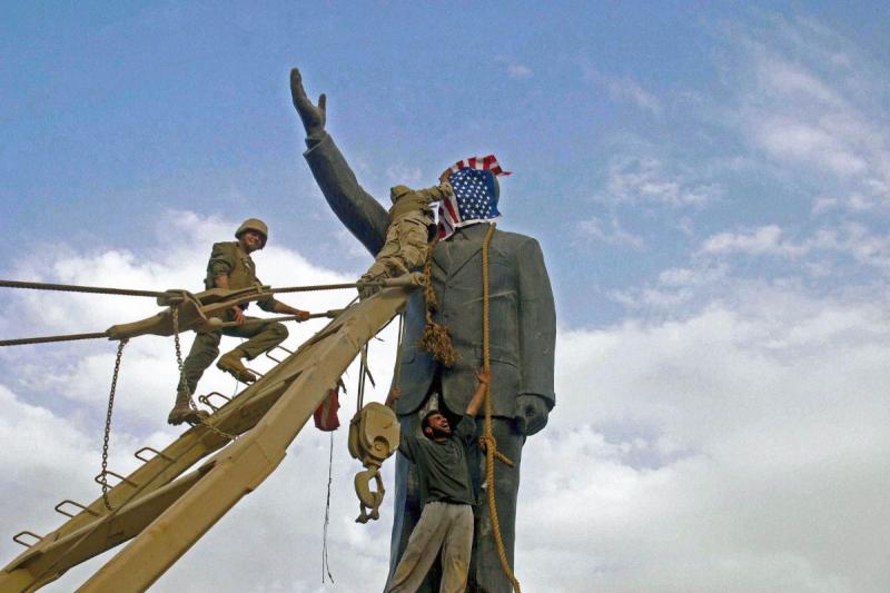 Photo: A U.S. Marine covers the face of a statue of Saddam Hussein with a U.S. flag before the statue  was toppled. Baghdad, Iraq 2003 Archival Pigment Print #2961