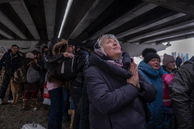 Photo: A woman prays as she escapes to safety from advancing Russian forces in her city, Irpin,  Ukraine 2022 Archival Pigment Print #2972