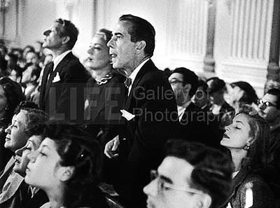 Actors Danny Kaye, June Havoc and Humphrey Bogart, with wife, actress Lauren Bacall sitting beside him, listening intently a hearing regarding communists in the film industry, 1947